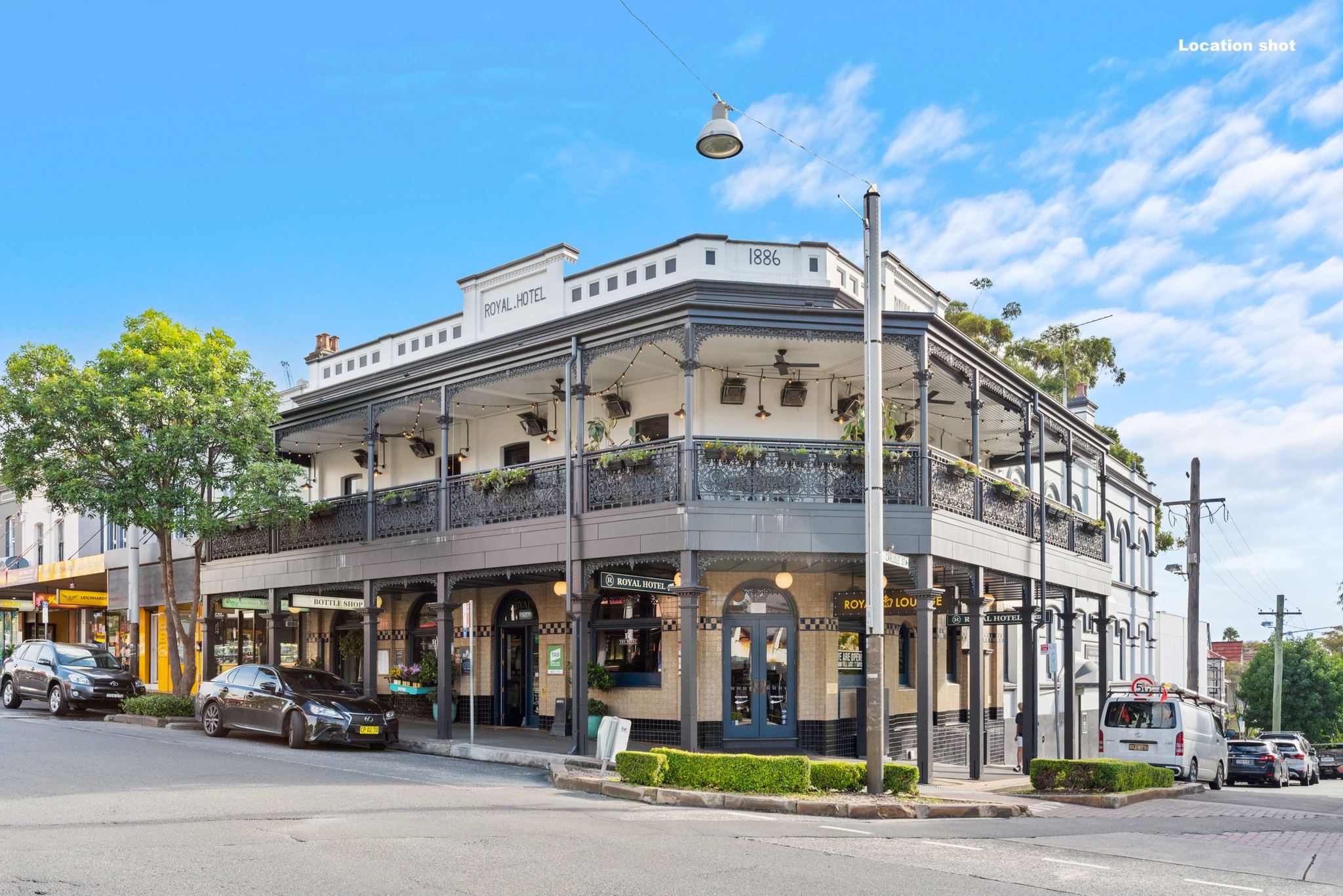 Heritage corner hotel with iron-lace balconies on a leafy Sydney street