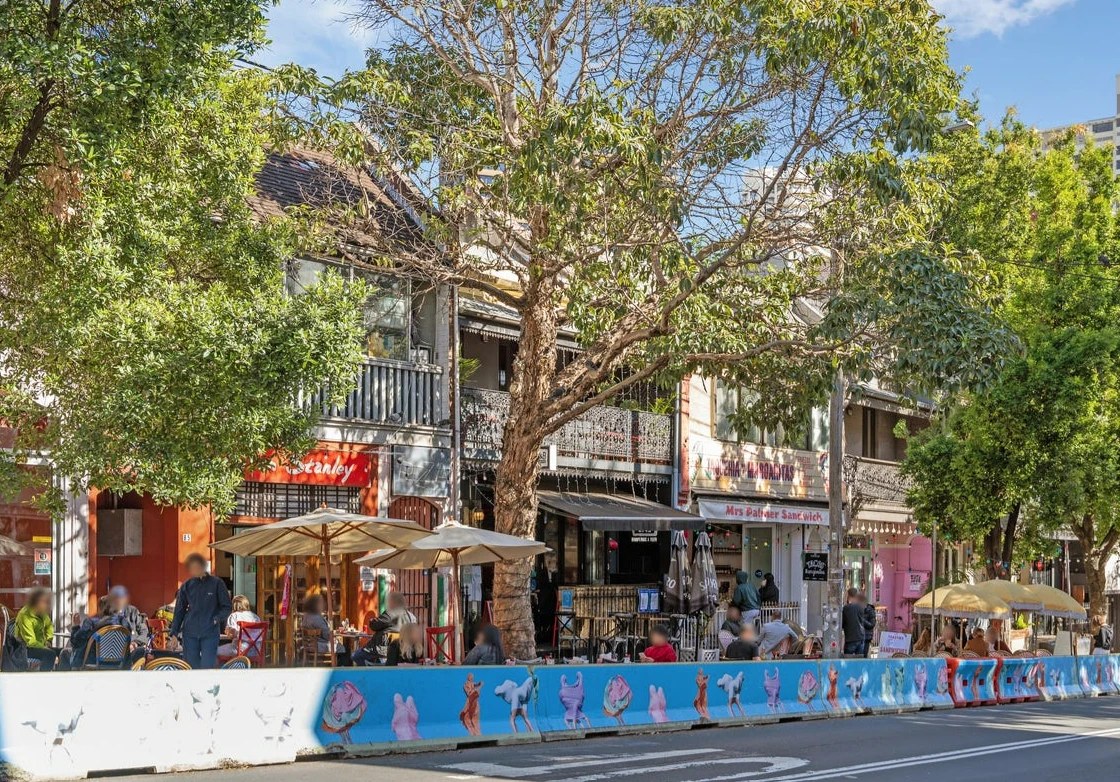 Outdoor cafe tables under the trees on a Darlinghurst street